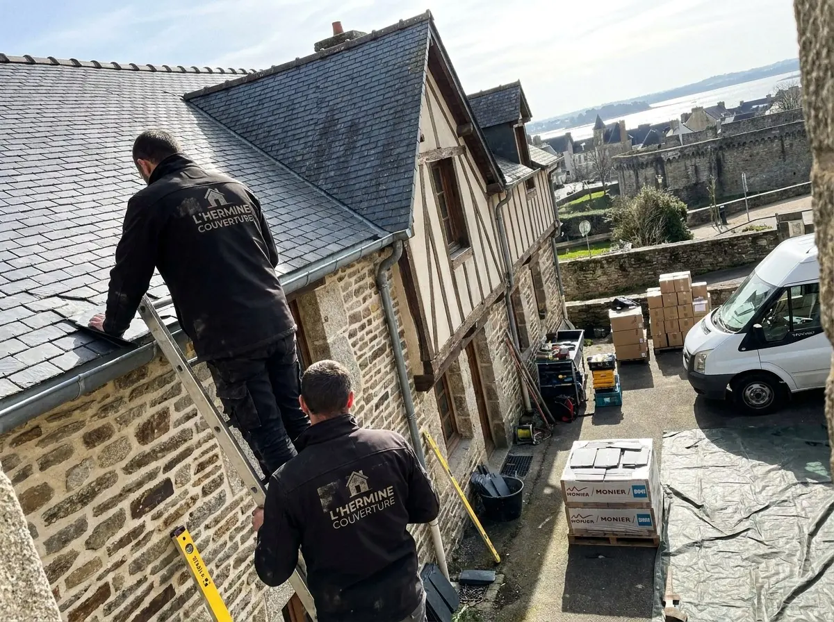 Couvreurs de L'Hermine Couverture sur un toit d'ardoise d'une maison à pans de bois à Vannes, remparts et golfe du Morbihan au loin